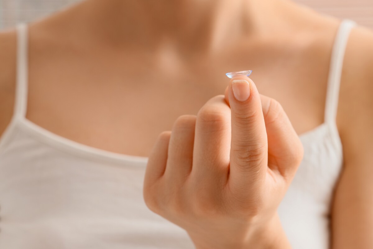 Person holding a soft contact lens on their fingertip before insertion.
