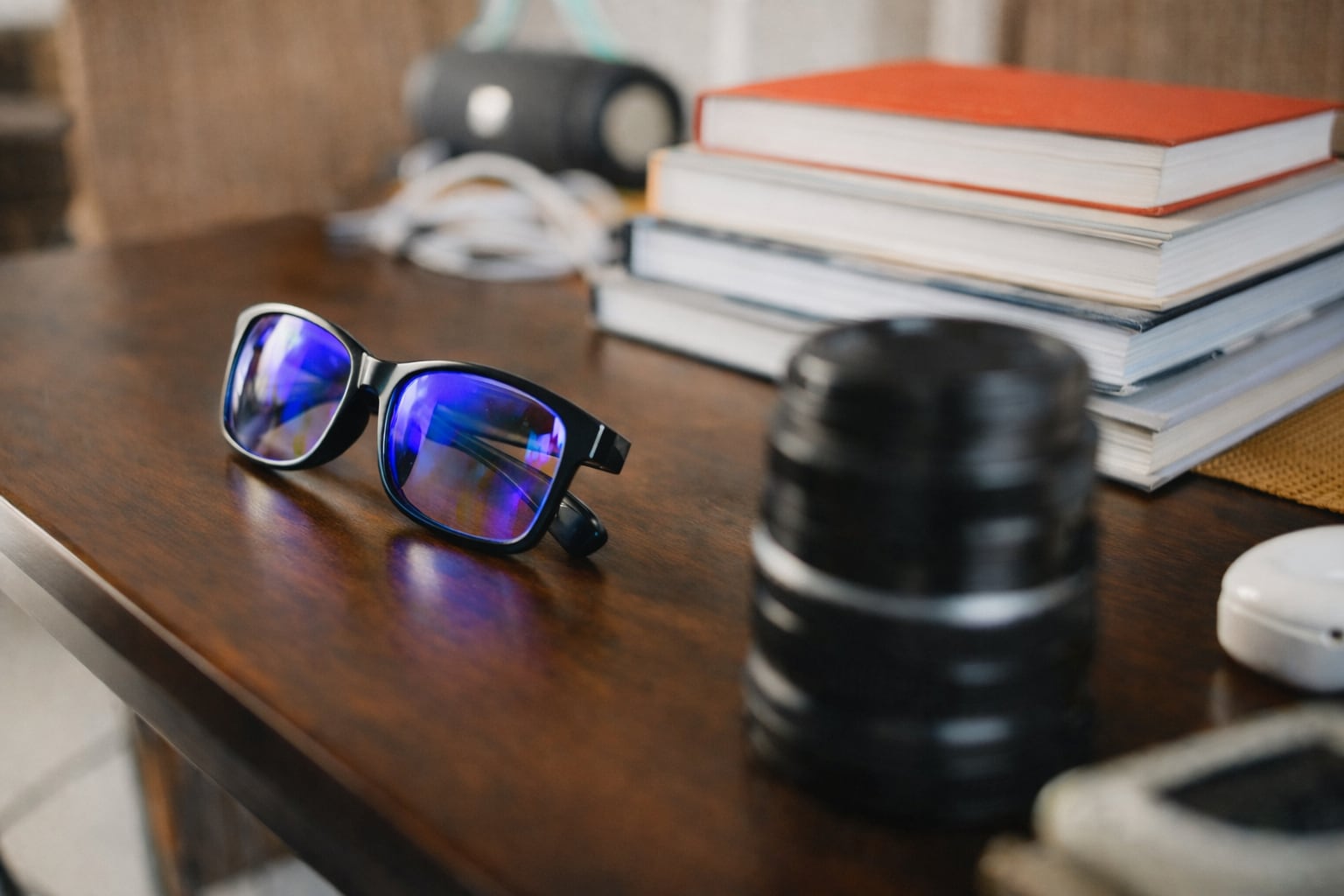 Blue light blocking glasses with blue reflective lenses on a wooden desk next to a stack of books