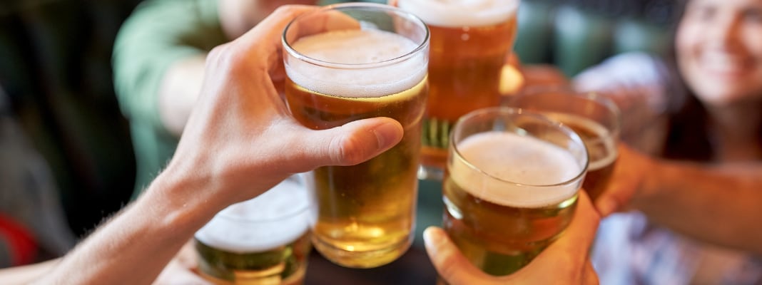 Group of people clinking glasses of beer in a social setting.