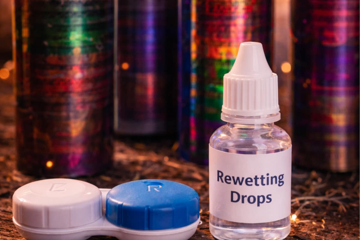Contact lens case and rewetting drops beside fireworks on a table