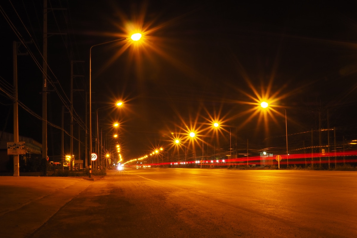 Nighttime street scene with bright streetlights creating starburst glare effects.