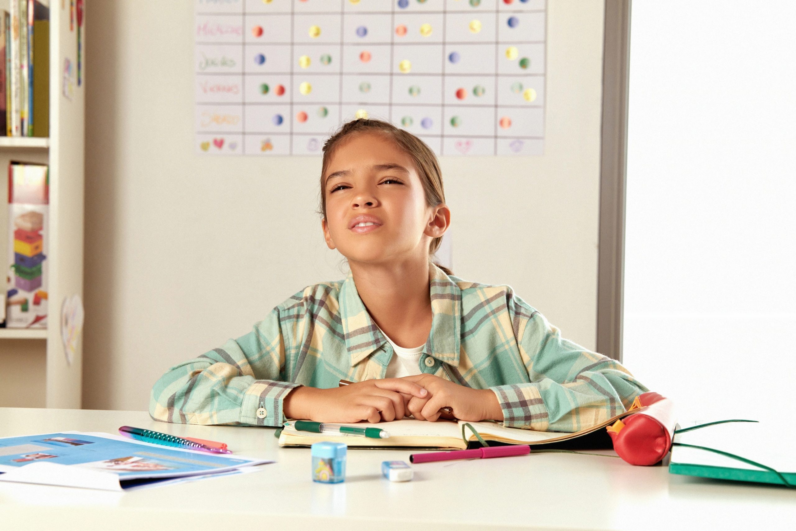 Warning Signs Your Child May Have a Vision Problem: child squinting at a desk during homework in a classroom-like setting.