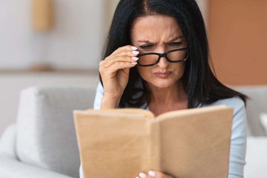 woman-with-glasses-squinting-to-read-book