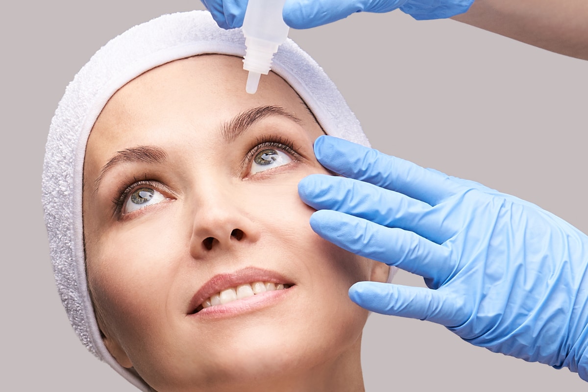 Woman looking up while a nurse applies eyedrops